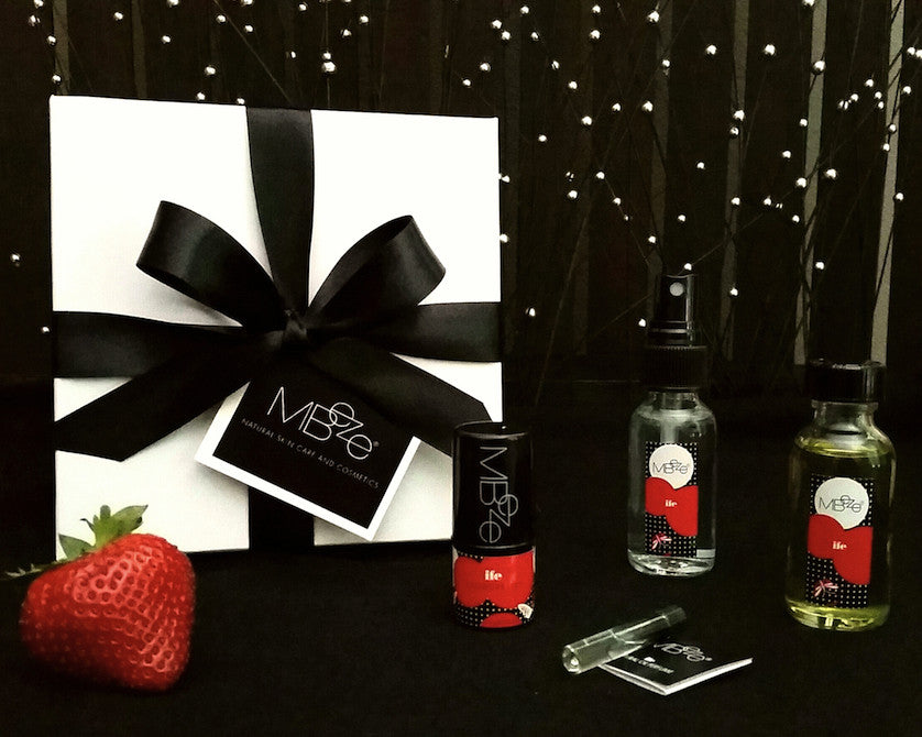 MBeze Ife Mini Gift Set with gift box, including Deodorette, Body Mist Traveler, Body Oil Traveler, and Perfume Sample, with large strawberry in front.